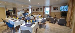 un restaurant avec des tables et des chaises blanches et une télévision dans l'établissement Hotel Belle Vue, à Souillac