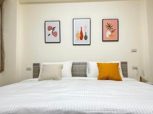 een slaapkamer met een bed met vier foto's aan de muur bij Hourlight Homestay in Ch'iung-lin