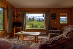 a living room with a table and a large window at Mica Mountain Lodge & Log Cabins in Tête Jaune Cache