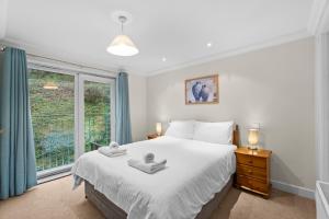 Un dormitorio con una cama grande y una ventana en Crylla Valley Cottages, en Saltash