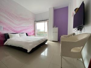 - une chambre avec un lit et un mur violet dans l'établissement Mang Yi Zhan Inn, à Kenting