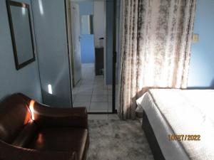 ein Schlafzimmer mit einem Bett, einem Stuhl und einem Fenster in der Unterkunft PS GOOD TIME GUEST HOUSE in Klerksdorp