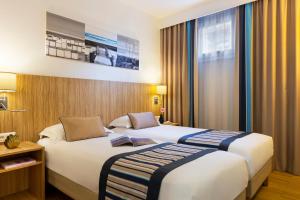 um quarto de hotel com duas camas e uma janela em Citadines Croisette Cannes em Cannes