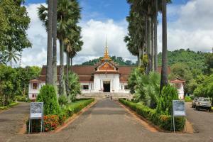 a temple with palm trees in front of it at Moon's house LuangPrabang in Luang Prabang