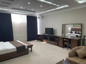 een hotelkamer met een bed, een bureau en een bank bij Grand Shirin Palace Bux in Bukhara