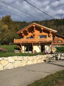 a log cabin with a stone wall in front of it at Chalet Anzac Chalet 5 Etoiles en Rondins Tout Neuf Unique dans les Aravis in Les Villards-sur-Thônes