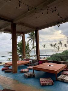 um pátio com mesas e cadeiras e o oceano em Funky Sol - Sunset Rooftop Bar, Hotel & Restaurant em Weligama