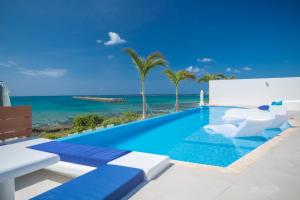 einen Pool mit Stühlen und das Meer im Hintergrund in der Unterkunft Ronsard Resort IRABU in Miyako-jima