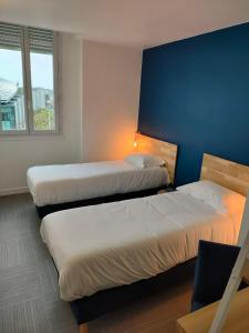 2 camas en una habitación con una pared azul en La Marinière Hôtel Restaurant, en Saint-Malo