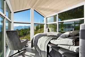 a bedroom with a bed and a chair in front of windows at Northern Light cottage 1 