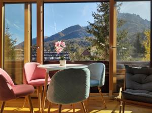 stół i krzesła w pokoju z dużym oknem w obiekcie Appartement Bella Vista w mieście Kranjska Gora