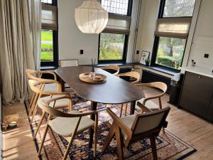 a dining room with a table and chairs and windows at Het Wylde Pad - Let’s go Wylde! in Twijzelerheide
