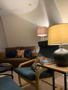 a living room with a couch and a table with a lamp at The Riding Gate Apartment in Kent