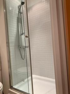 a shower with a glass door and a tub at The Riding Gate Apartment in Kent