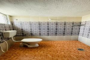 baño con aseo y pared de azulejos en Skyry Hotel Iyyapanthangal en Chennai