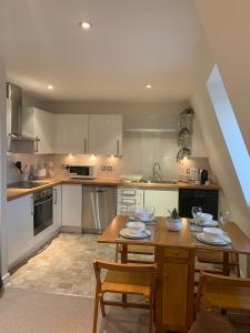 Una gran cocina con una mesa y sillas de madera. en The Riding Gate Apartment, en Kent