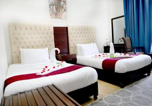 Cette chambre d'hôtel comprend 2 lits avec des touches de rouge. dans l'établissement Jabal Al Akhdar Grand Hotel, à Jabal Al Akhdar