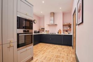 a kitchen with black cabinets and a wooden floor at No2 St Peters Street in Winchester