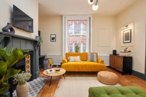 a living room with a yellow couch and a fireplace at No2 St Peters Street in Winchester