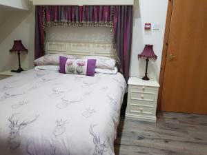 a bedroom with a white bed with a deer print on it at Culag Lochside Self Catering in Luss