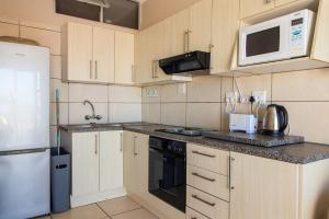 a kitchen with wooden cabinets and a white refrigerator at Unit 18 Kei Sands Resort in Kei-mouth Village +15 photos