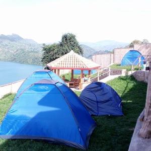 zwei blaue Zelte im Gras neben einem Pavillon in der Unterkunft Kivu Macheo eco-lodge in Kibuye