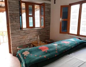 a bedroom with a bed with a green blanket at Himalayan Hills Village Retreat by StayApart, Ukhimath in Rudraprayāg +17 photos