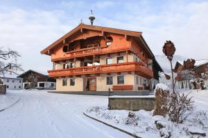 un gran edificio de madera con un balcón en la nieve en Starmacher Hof, en Itter