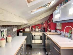 eine große Küche mit roten Wänden und Edelstahlgeräten in der Unterkunft Magnifique appartement vue mer et parking privé ! in Grasse