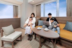 a family sitting on a couch in a room at karaksa hotel grande Shin-Osaka Tower in Osaka