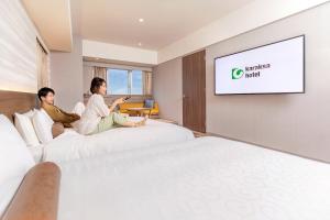 a man and woman sitting on beds in a hotel room at karaksa hotel grande Shin-Osaka Tower in Osaka