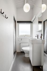 ein weißes Bad mit einem WC und einem Fenster in der Unterkunft Remarkable 2-Bed Beach House 12J in Brenderup