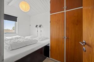 Schlafzimmer mit einem Bett und einem Holzschrank in der Unterkunft Remarkable 2-Bed Beach House 12J in Brenderup