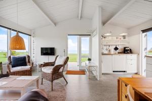 a living room with a table and chairs and a kitchen at Sct Knudsborg - 12J - Summerhouse on the beach in Brenderup