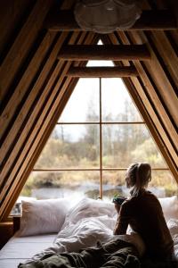 une femme assise au lit devant une fenêtre dans l'établissement Jõemaja, à Oiu