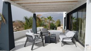 um pátio com cadeiras e uma mesa na varanda em Villa Isabella em Cómpeta