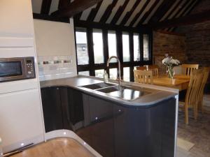 a kitchen with a sink and a table with chairs at The Longhouse, Brecon Beacons (King & Twin) in Brecon