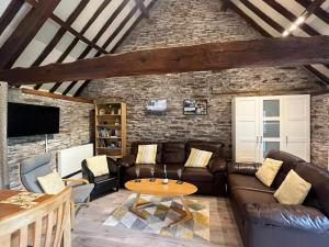 a living room with a leather couch and a table at The Longhouse, Brecon Beacons (King & Twin) in Brecon