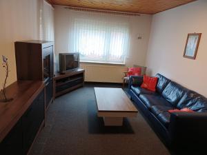 a living room with a leather couch and a tv at Ferienhaus Birkenallee in Papenburg