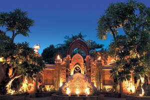 a building with lights and palm trees at night at Sawasdee Village in Kata Beach