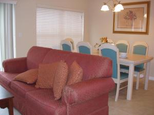 ein Wohnzimmer mit einem roten Sofa, einem Tisch und Stühlen in der Unterkunft Four Bedroom Villa in Coral Cay in Kissimmee