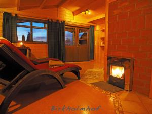 a living room with a fireplace with a couch and a chair at Birkholmhof in Bärnau