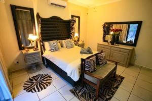Schlafzimmer mit einem großen Bett mit einem Kopfteil aus Holz in der Unterkunft Ukweza Guest House in Marloth Park
