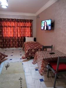 una camera con due letti e una TV a parete di Marrakech Hôtel Résidence a Marrakech