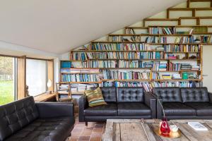 a living room with two couches and a large book shelf at Het Verblijf in Sint-Martens-Lennik
