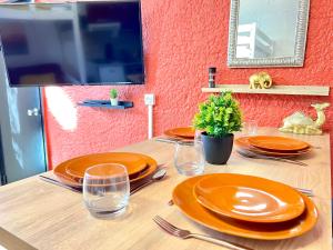 a table with orange plates and glasses and a mirror at ~ Le riad ~ Studio 1/4 Pers, porte du Futuroscope in Chasseneuil-du-Poitou