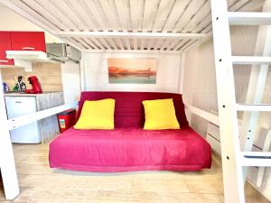 a red bed in a room with two yellow pillows at ~ Le riad ~ Studio 1/4 Pers, porte du Futuroscope in Chasseneuil-du-Poitou