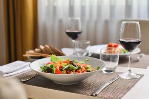 uma mesa com uma tigela de salada e copos de vinho em Hotel San Giorgio em Fiuggi