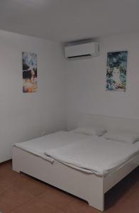 białe łóżko w pokoju z dwoma zdjęciami na ścianie w obiekcie Apartmán - súkromie v meste (1) w Bratysławie