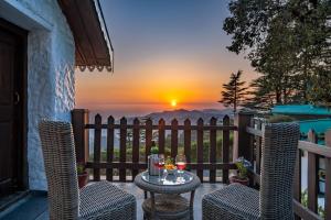 a patio with a table and chairs with a sunset at Rokeby Manor in Mussoorie
